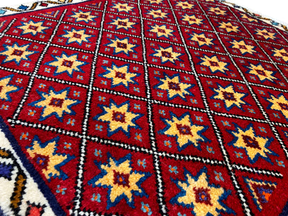 Gros plan sur le tapis : losange rouge avec des étoiles jaunes et bleues