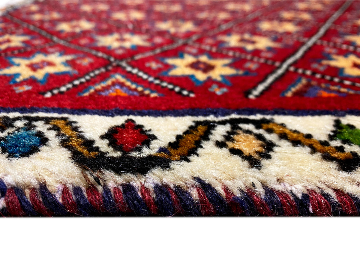 Détail du tapis : motif rouge et bleu avec des franges sur le bord inférieur